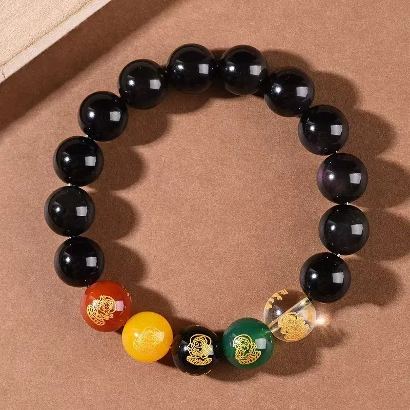 Close-up of a polished crystal bracelet with rainbow eye obsidian beads in a single circle design on a wrist.
