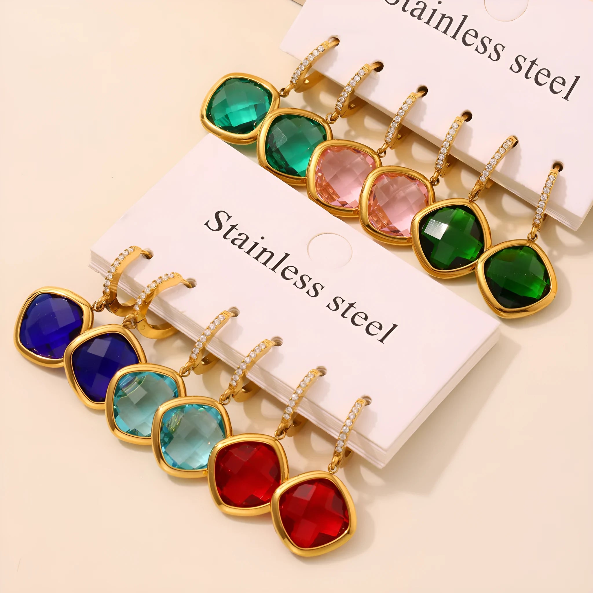 Mioli transparent cut Czech glass geometric square stud earrings in gold tone with blue zircon centre stone on white background