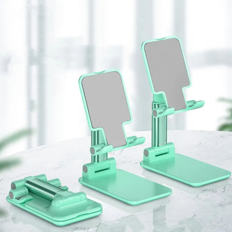 White folding telescopic mobile phone bracket holding a smartphone on a desktop.