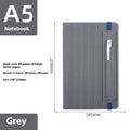 A5 faux leather notebook with pen insert and strap, open on a desk showing lined pages