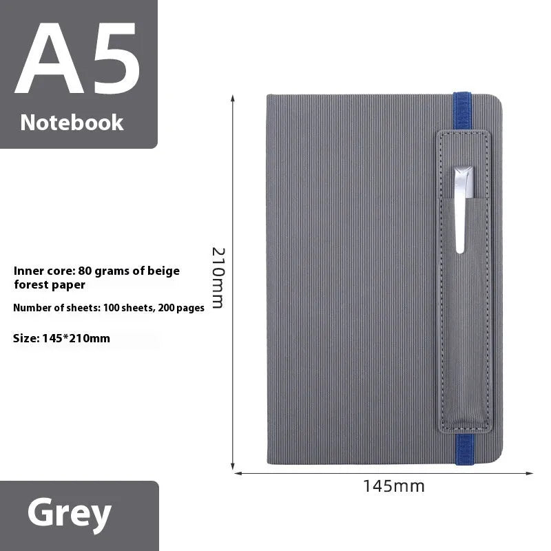 A5 faux leather notebook with pen insert and strap, open on a desk showing lined pages