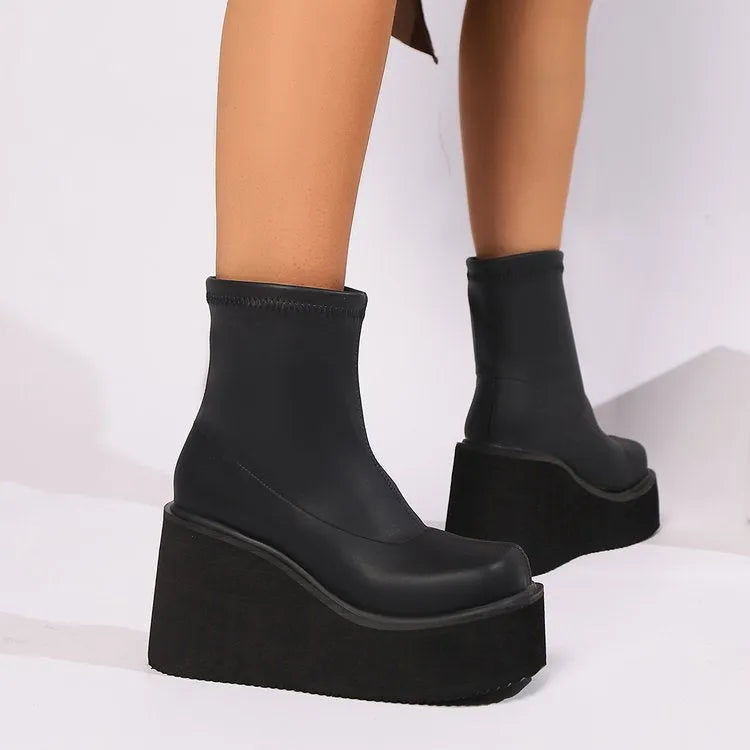 Plus size black wedge heel ankle boots with a round toe and waterproof platform on a wooden floor.