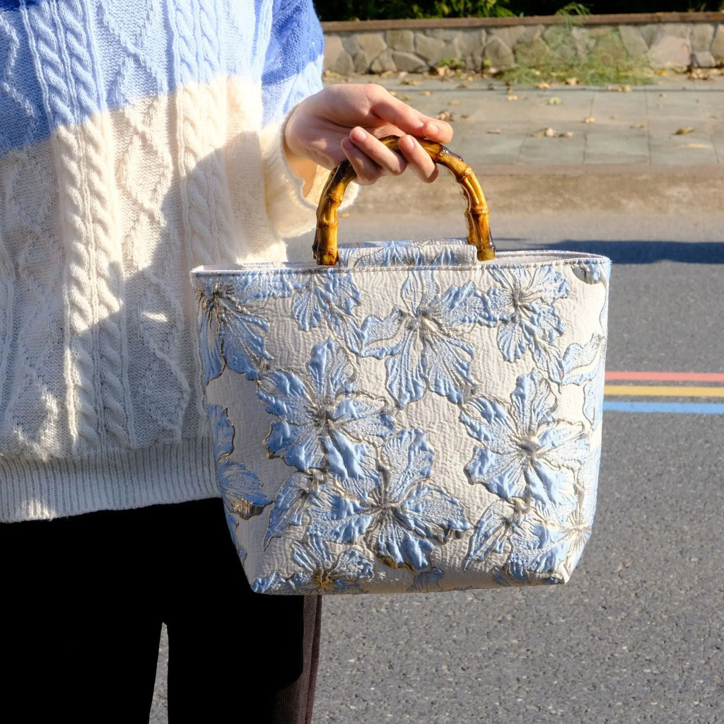 Women's light blue canvas shoulder bag with bronzing flower detail showing horizontal square shape and double straps