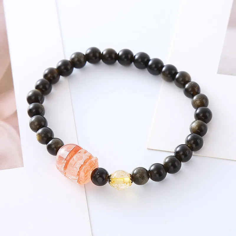 Handmade gold obsidian and red flower bead Pi Xiu bracelet on wrist, ethnic retro style.