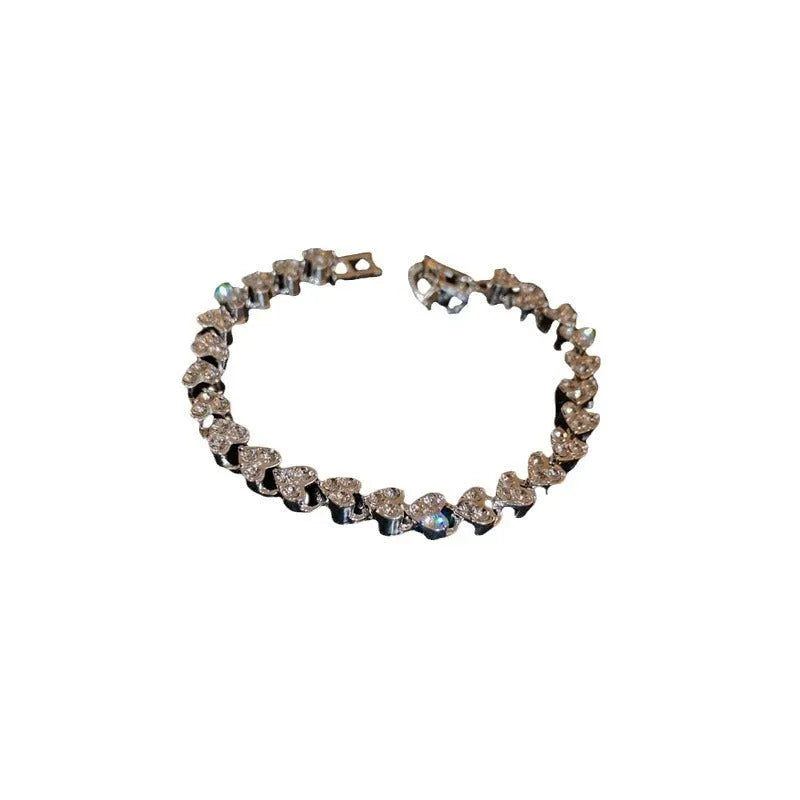 Silver metal heart-shaped bracelet with inlaid zircon on a plain background