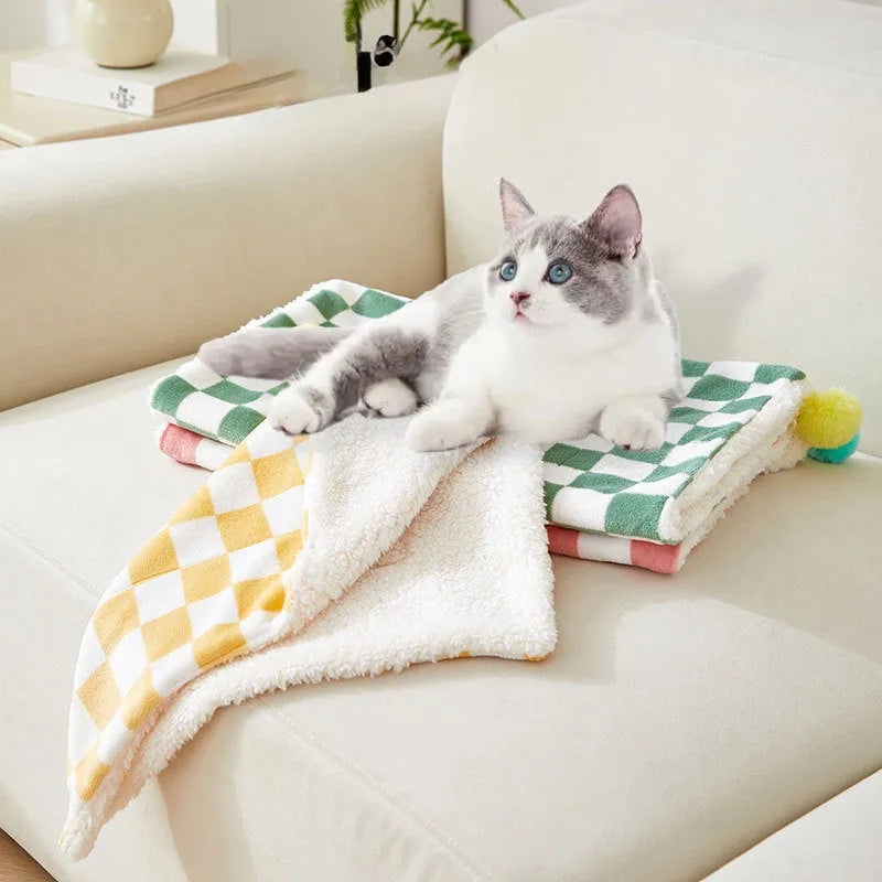 Soft plaid pattern pet blanket with fur ball decoration on a sofa
