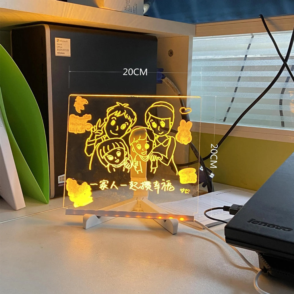 DIY acrylic LED message board lamp on a desk with colourful writing, showing USB cable and pens.