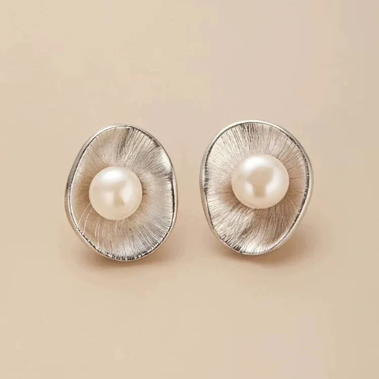A pair of sterling silver geometric stud earrings featuring a central simulated pearl.
