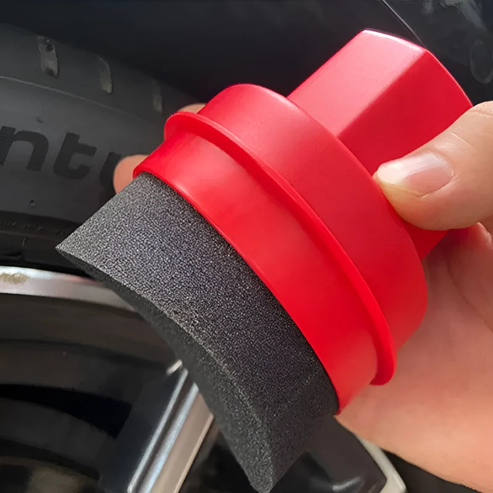 Black and red hand-held car tyre polishing sponge brushes with lids on a workbench.