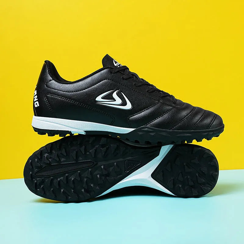 Low-top outdoor soccer shoes in a black and blue broken nails colourway on a turf background.