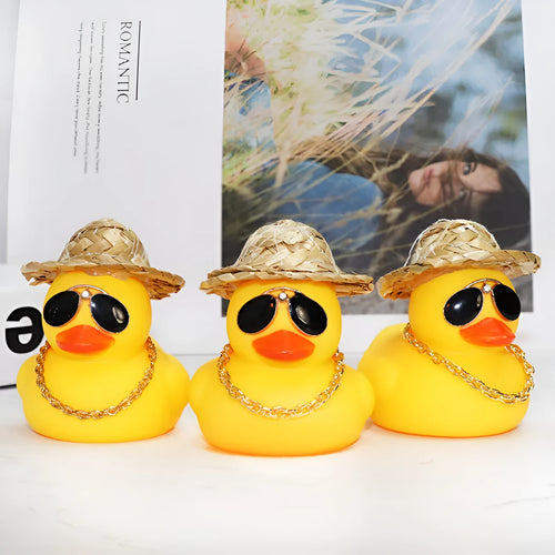 Yellow duck cartoon character wearing a straw hat, a car dashboard ornament with miniature sunglasses accessory.