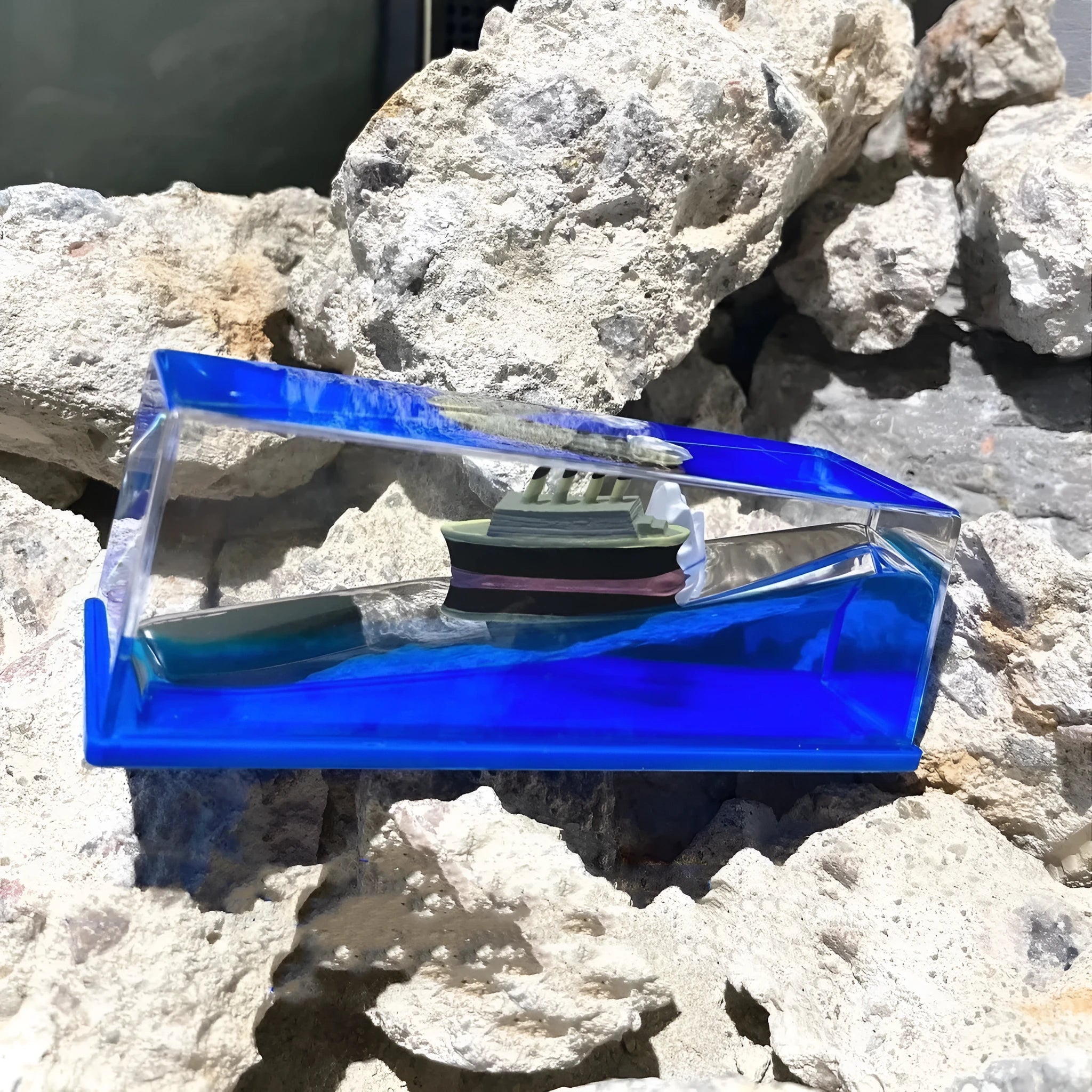Fluid drift bottle with floating astronaut decoration in acrylic resin, black pearl pirate ship style, on a wooden desk.