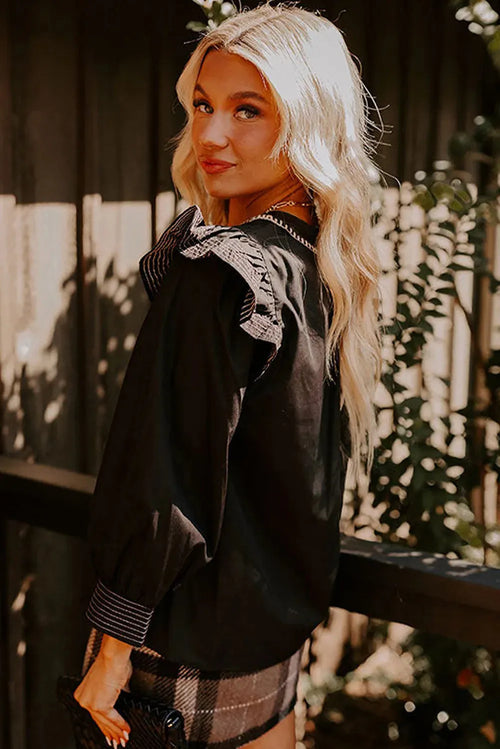Black V-neck long sleeve blouse with ruffle trim and contrast stitching.