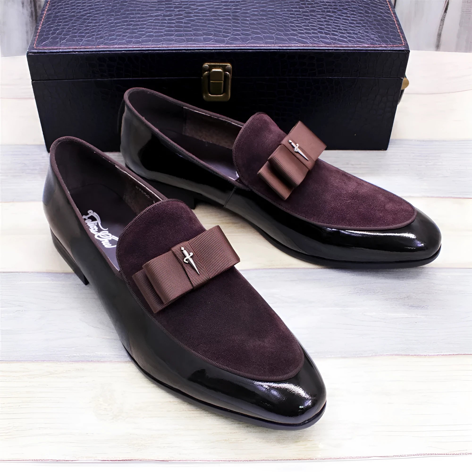 Men's glossy black patent leather low-top shoes with a tassel detail on a white background.