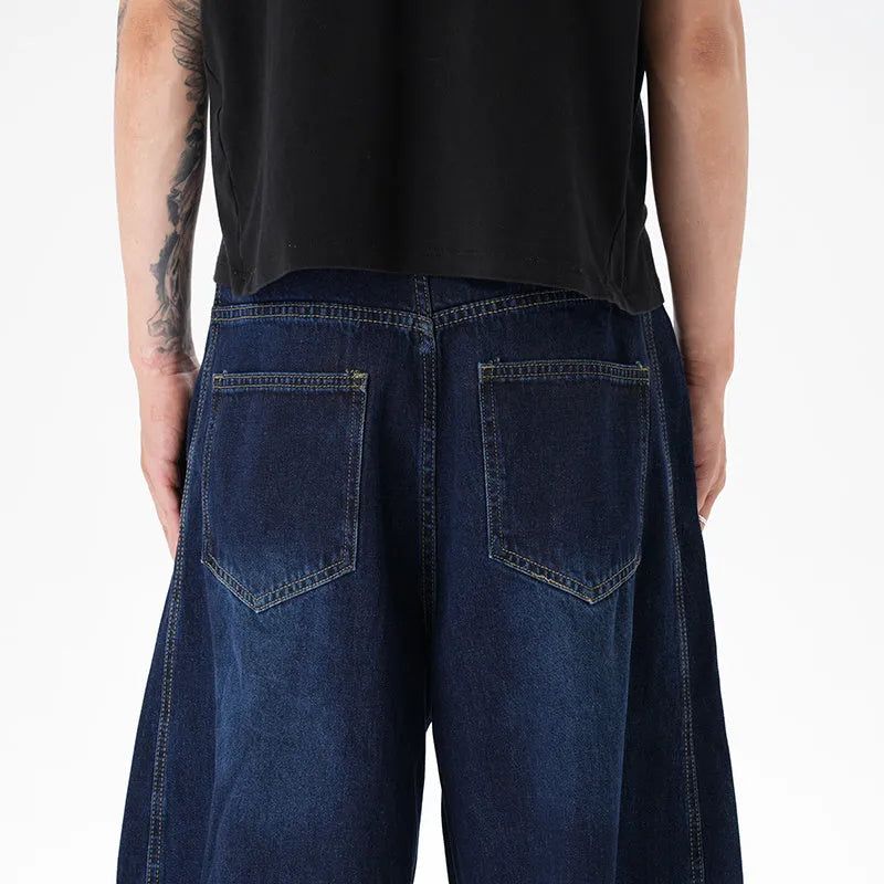 Dark blue washed distressed wide leg machete jeans on a model, showing the denim fabric and relaxed fit.