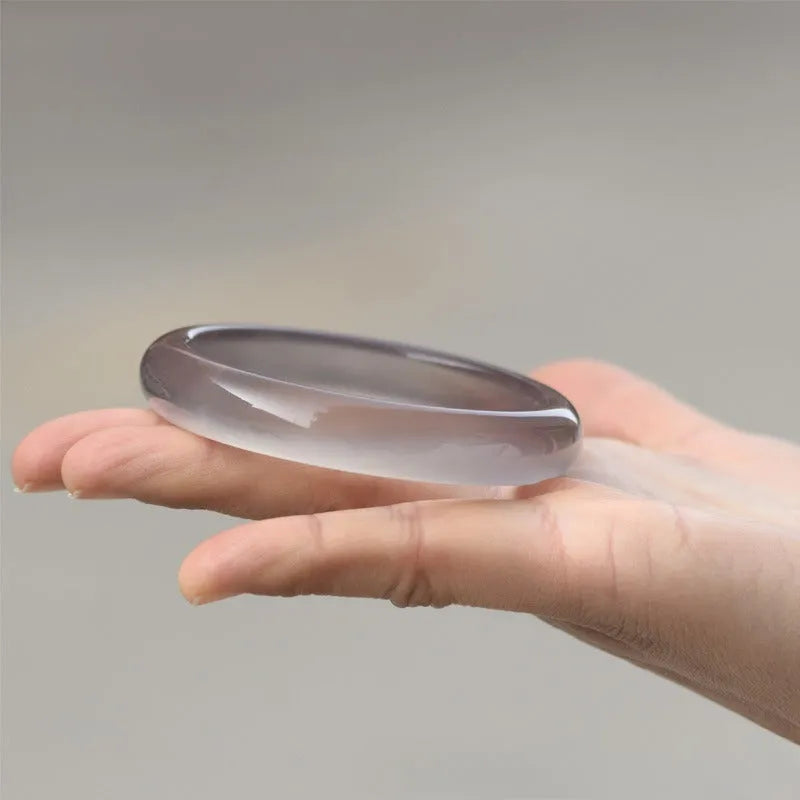 Women's dark grey agate bracelet in a circular design on a wrist.