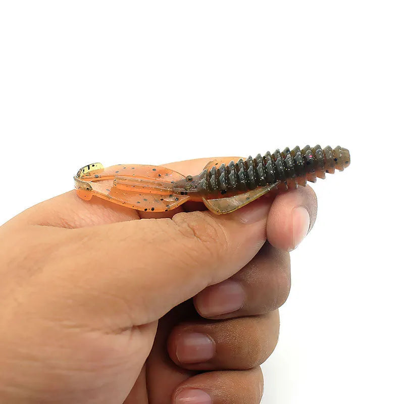 PVC soft plastic fishing lure in a worm shape, shown in a selection of different colours on a tackle box.