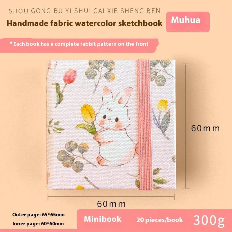 Feiluniao handmade fabric watercolour notebook with illustrated cover, open to show blank paper pages.
