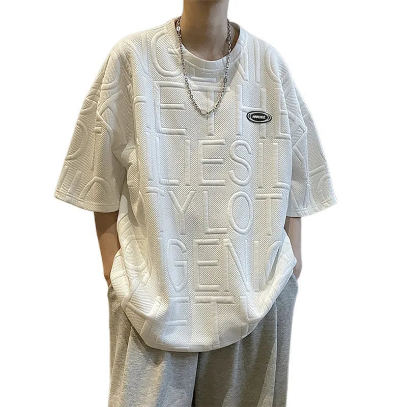Men's grey loose-fit short sleeve t-shirt featuring a raised three-dimensional letter design on the front.