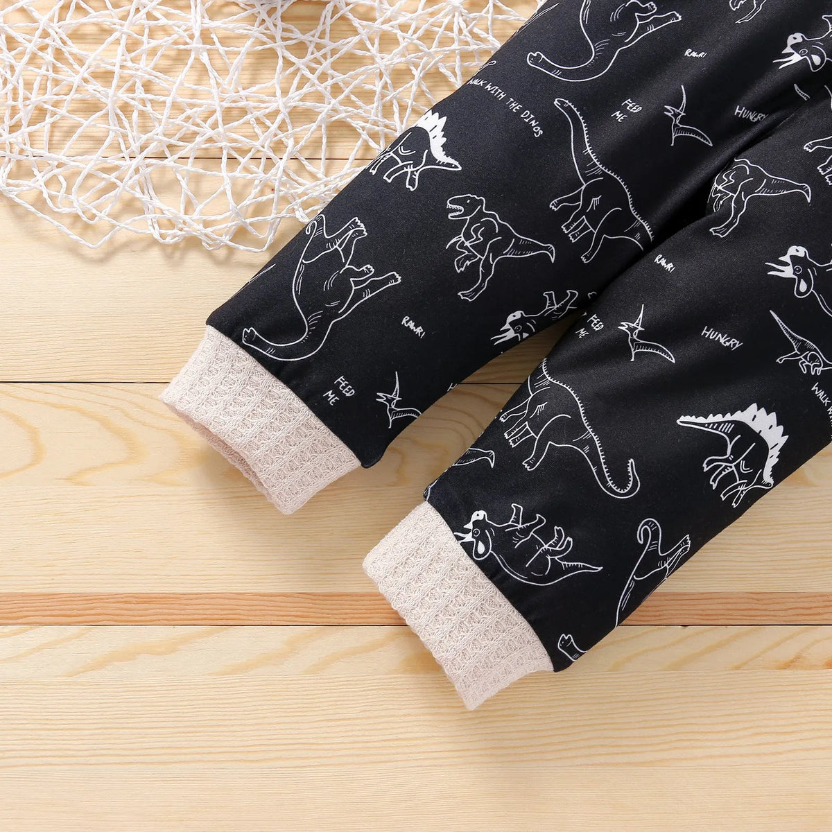 Cotton children's pants suit with dinosaur cartoon pattern in beige, pullover top and trousers set on child model
