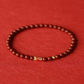 Natural cinnabar koi bracelet with golden ball in national style on a wrist.