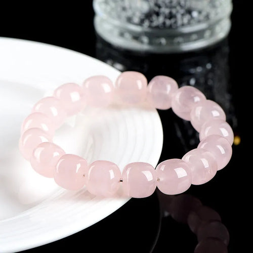 Close-up of a pink geometric bracelet with barrel-shaped crystal beads on a wrist.