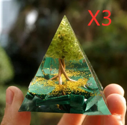 Clear epoxy resin pyramid ornament with natural crystal gravel inside on a wooden surface.