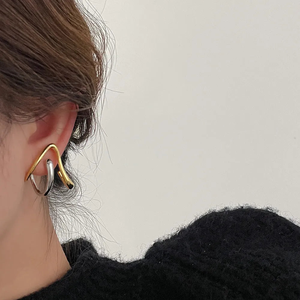Gold and silver irregular triangle alloy stud earrings with sterling silver needle on neutral background