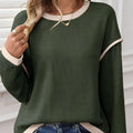 Women's beige knit top with green four leaf clover contrast trim on sleeves and neckline.