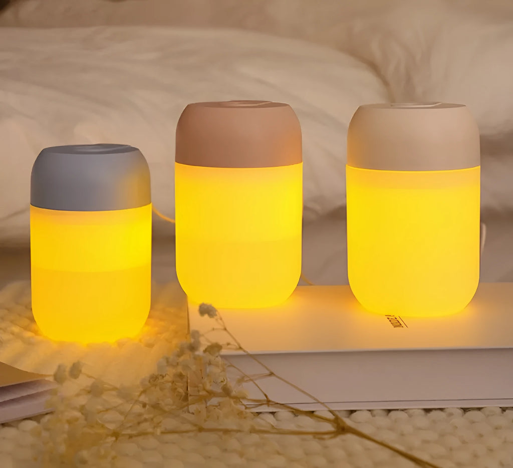 White cylindrical USB mini humidifier with charging cable on wooden desk