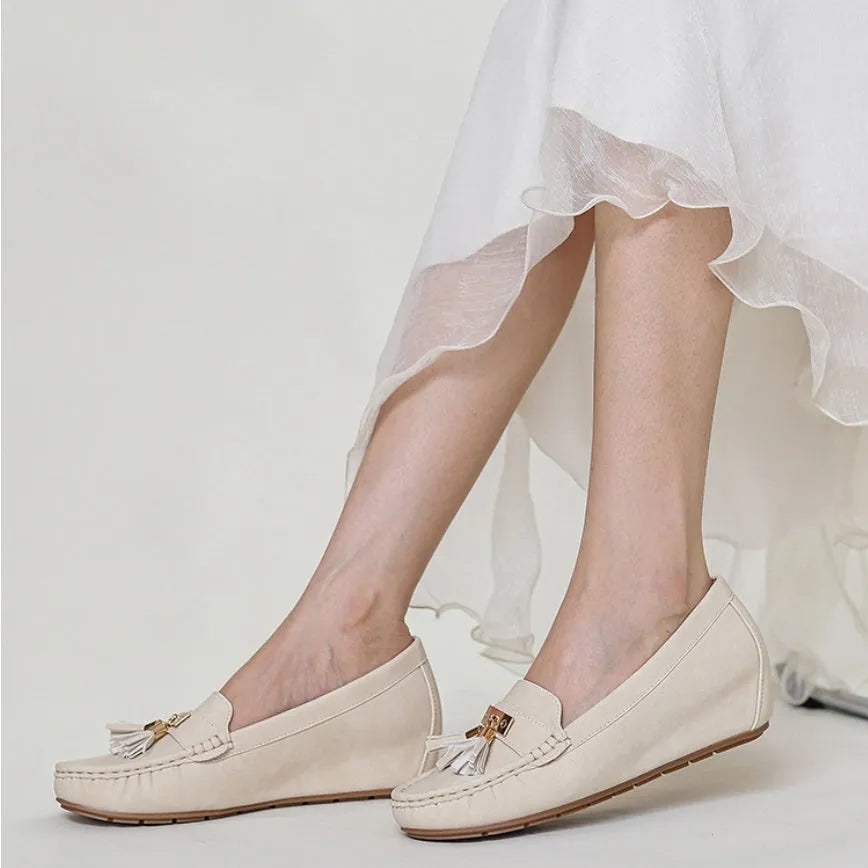 A pair of nude-coloured height-increasing shoe insoles with a round toe and a raised heel section.