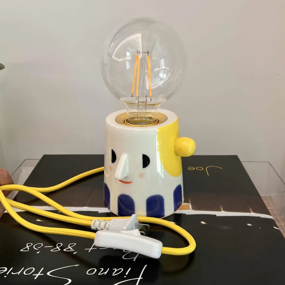 Handmade ceramic table lamp with a white ball headlight shade on a wooden table.