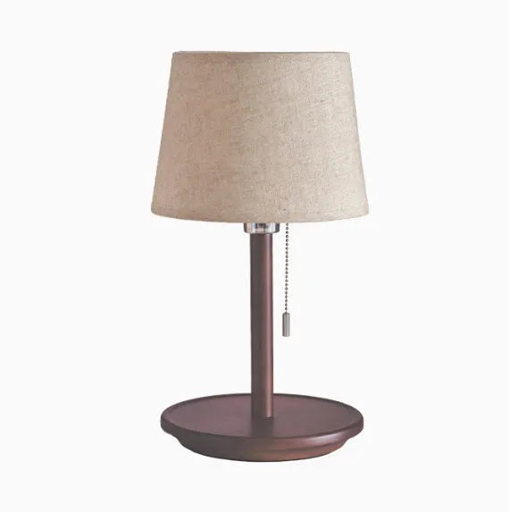 Walnut coloured solid wood bedside lamp with a white cloth shade and a cable switch.