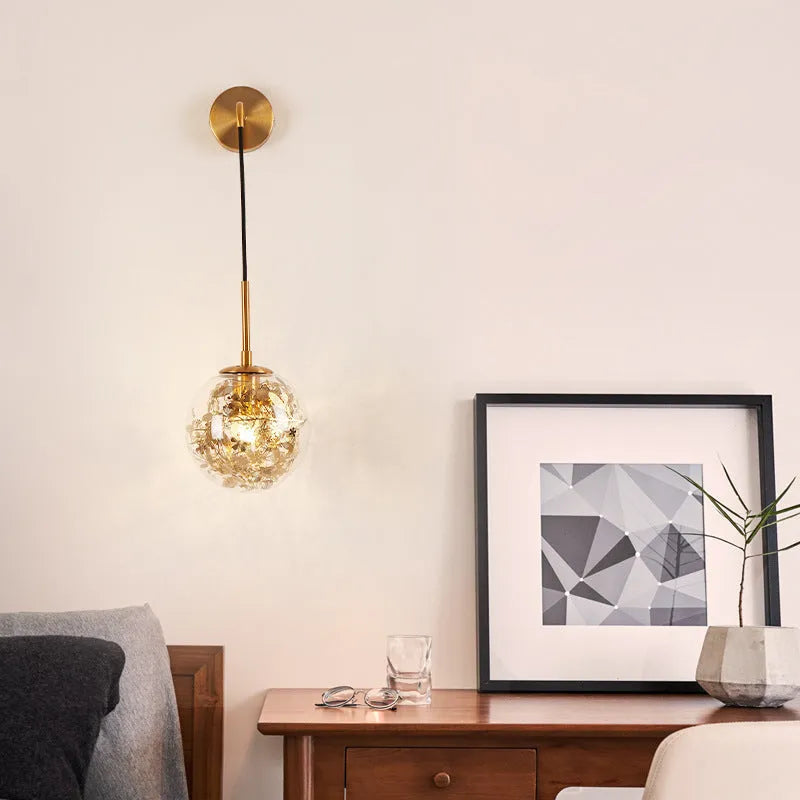 Modern glass wall mounted bedside lamp in golden flower finish on a white wall.