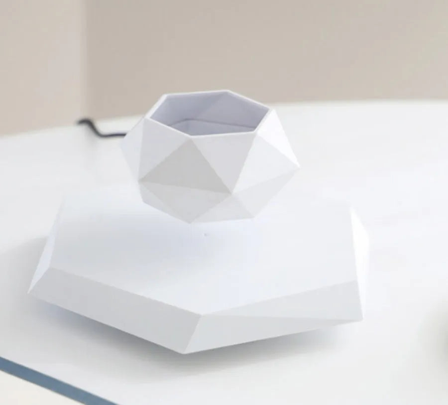 Hexagonal wood grain magnetic levitating flower pot floating above a circular black base on a desk.