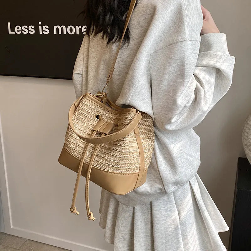 Brown woven straw women's crossbody bucket bag with a long adjustable strap.