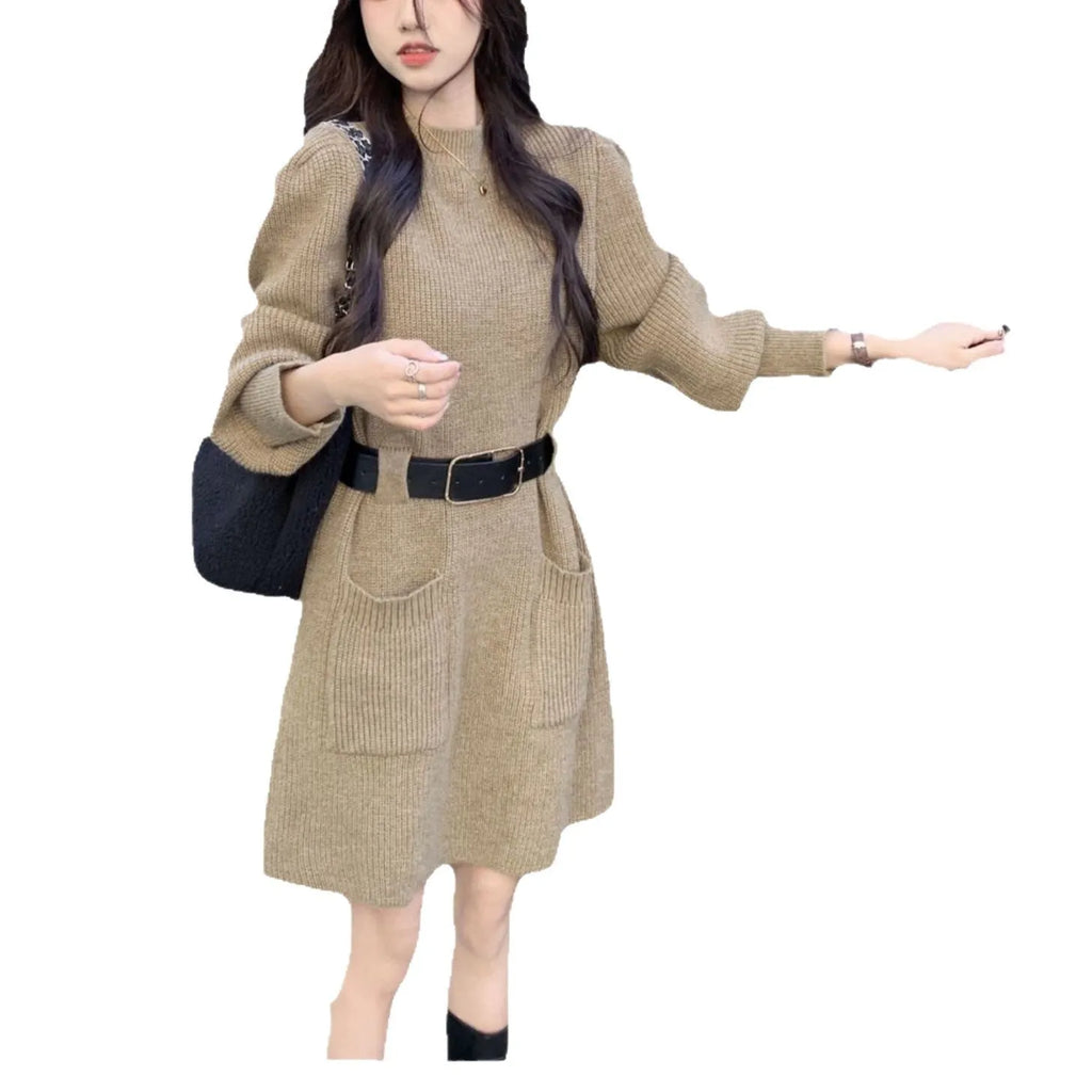 Women's long sleeve loose knitted dress in beige with a black belt, shown on a hanger.