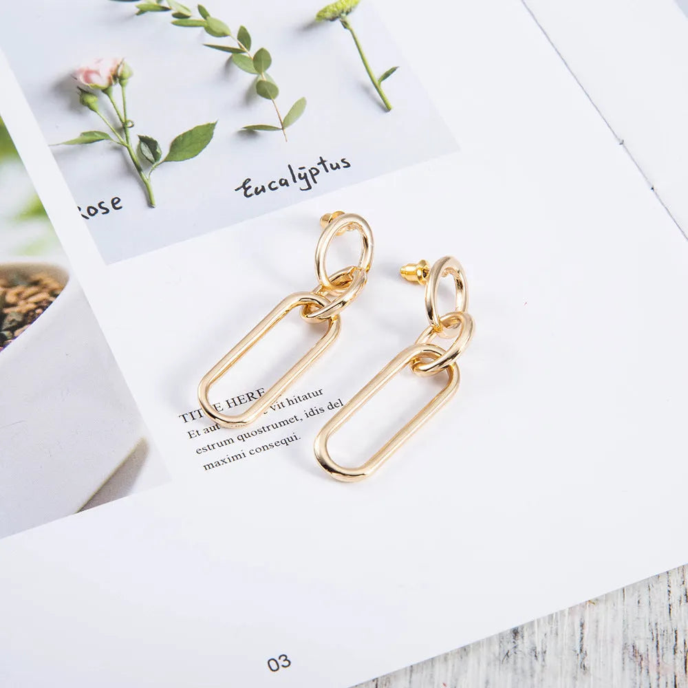 Geometric sterling silver colour hoop earrings with a ring and line design on a white background.