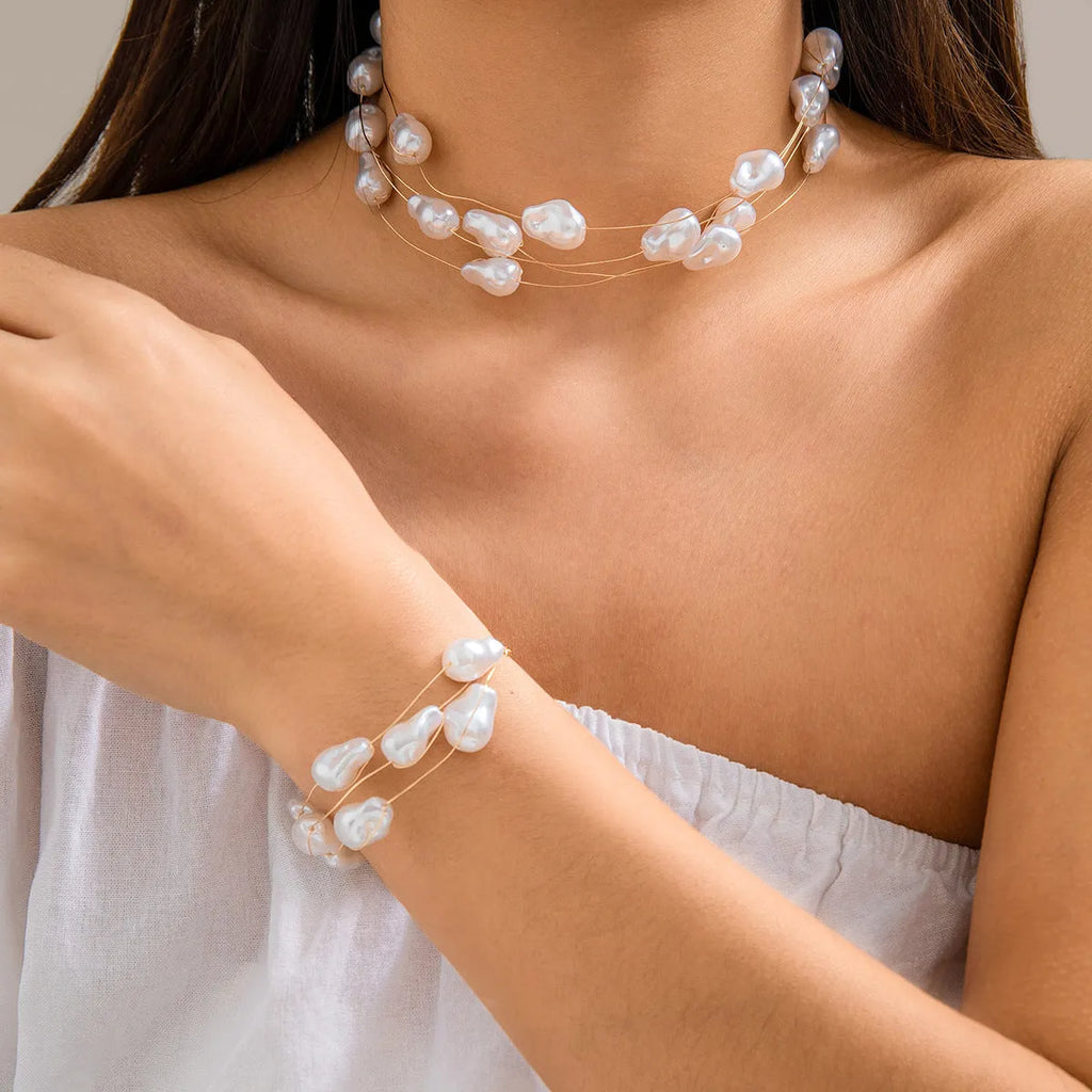 Gold-tone baroque imitation pearl necklace and bracelet set with U-shaped pendant on woman