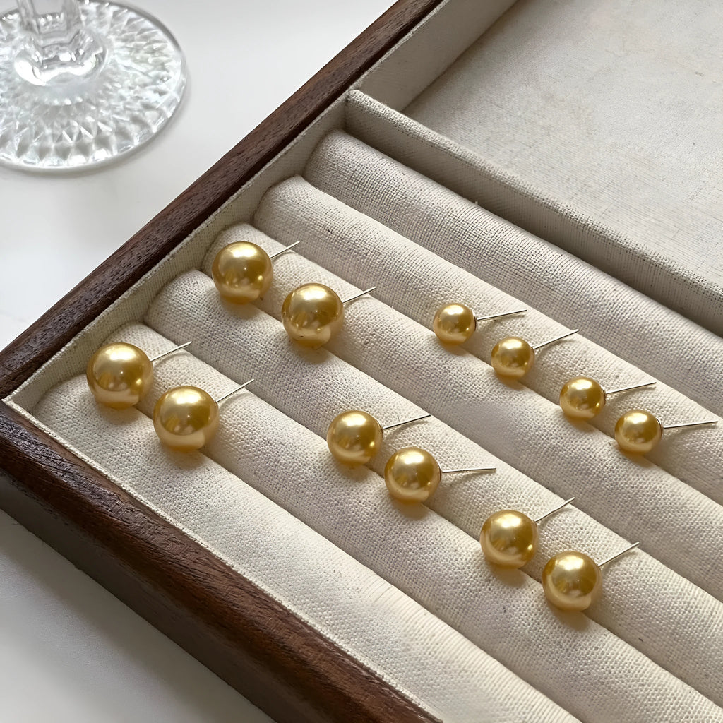 A pair of large pearl stud earrings with a geometric silver setting and an eight-point star detail.