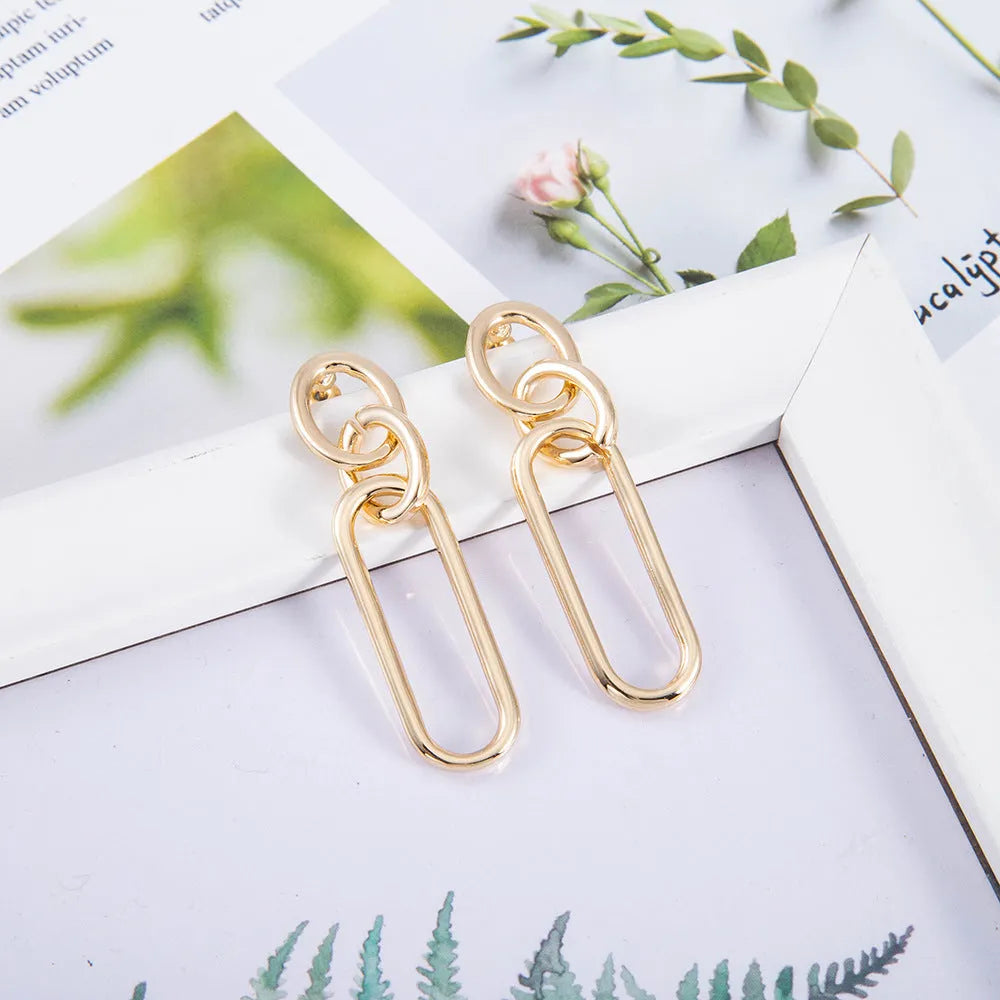 Geometric sterling silver colour hoop earrings with a ring and line design on a white background.