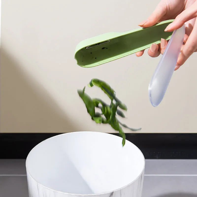 Dark green kitchen peeler with storage tube showing stainless steel blade and hanging hole on handle