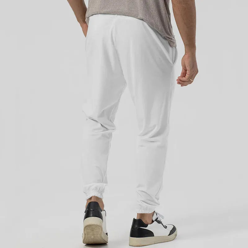 Man wearing grey loose tapered cotton blend track sweatpants with a straight leg.