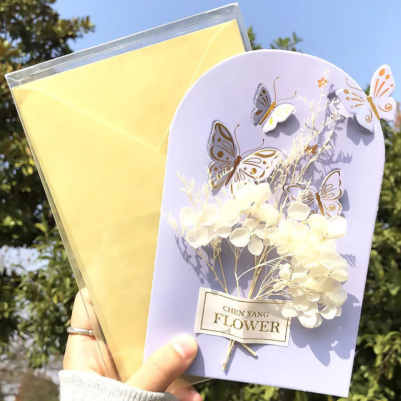 Handmade 3D butterfly-shaped greeting card with artificial flowers in a box, alongside its matching envelope.
