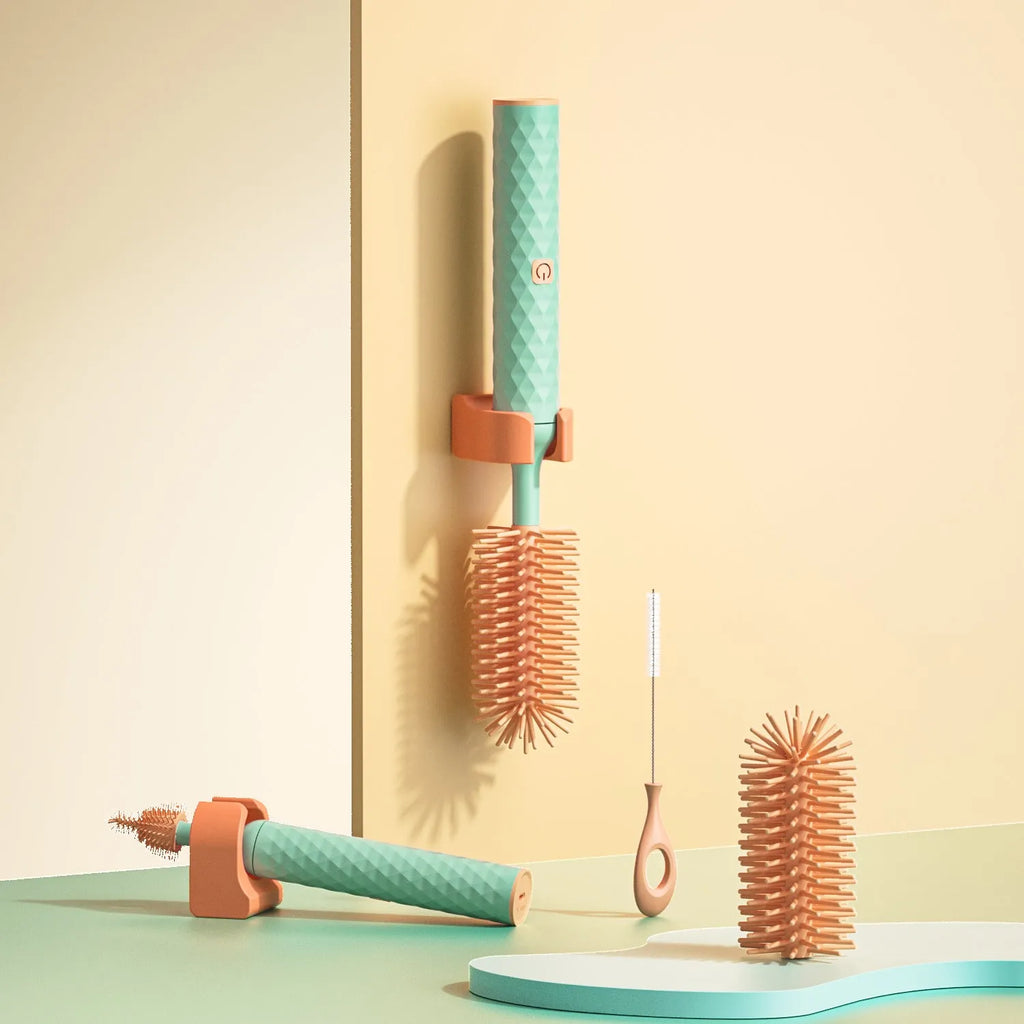 Pink and green electric baby bottle cleaning brush with rotating silicone head on a table