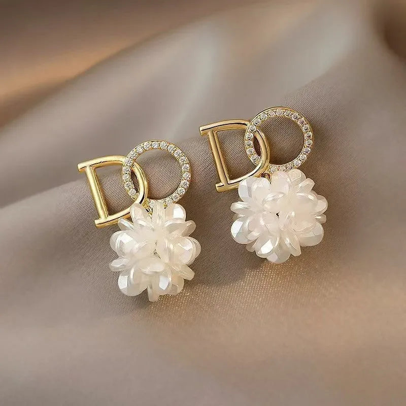 White acrylic DO letter embroidered ball stud earrings for women on light background
