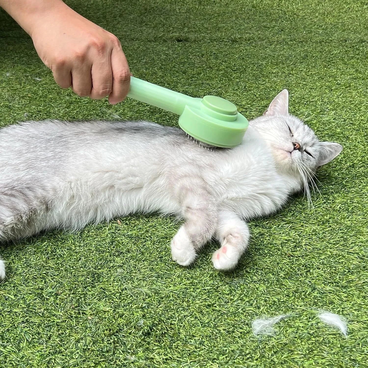 Green and yellow pet grooming brush with stainless steel teeth and a hanging loop for storage.