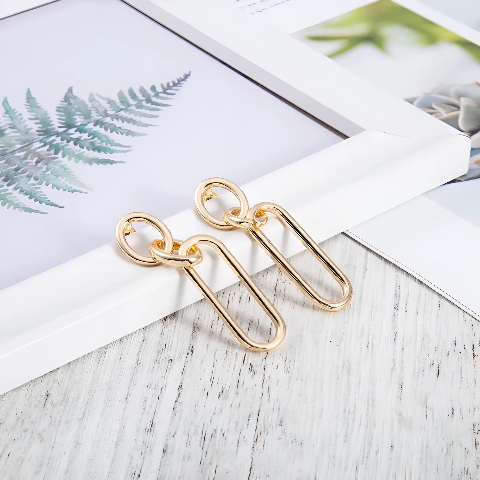 Geometric sterling silver colour hoop earrings with a ring and line design on a white background.