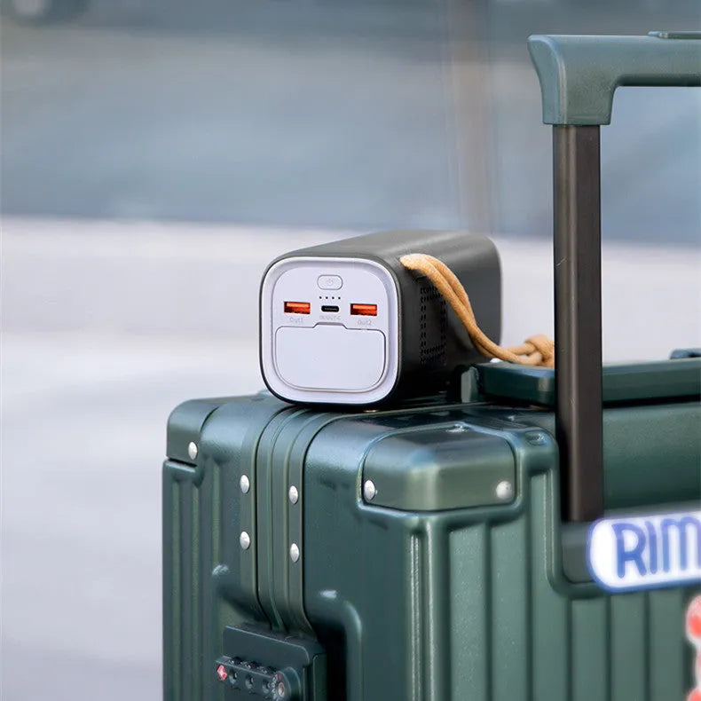 Black portable power bank with solar panel, showing USB ports and car charging socket