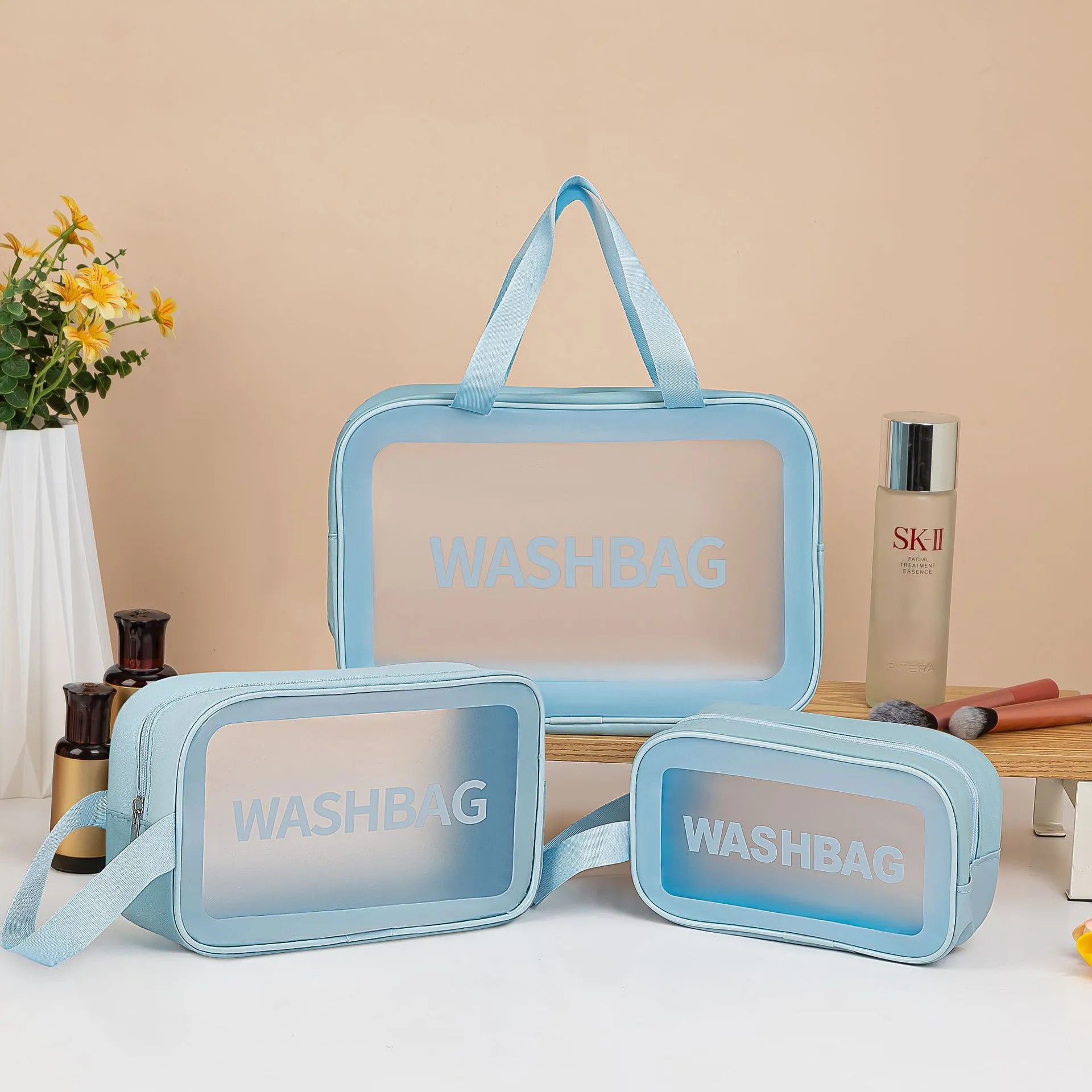 Large PVC transparent cosmetic bag three-piece set in various colours including beige, black, blue, pink, and white, empty and open on a flat surface
